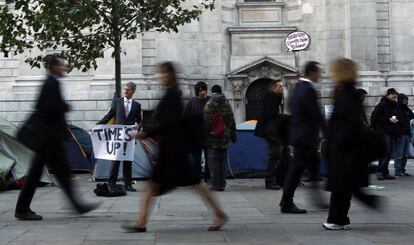 Un manifestante indignado, vestido con traje y corbata, sostiene un cartel con el lema 'Se acabó el tiempo' en la acampada a las puertas de la Catedral de St Paul, cerca de la bolsa de Londres.