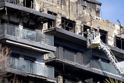 Dos bomberos subidos a una grúa limpian restos en el exterior del edificio incendiado, el 26 de febrero en Valencia. 