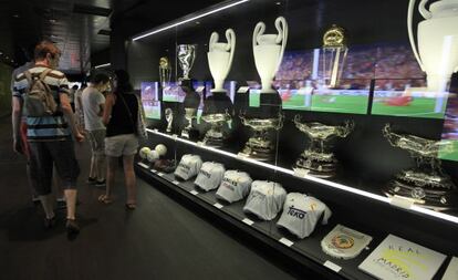 Visitantes del Santiago Bernabéu admiran las copas y equipaciones.