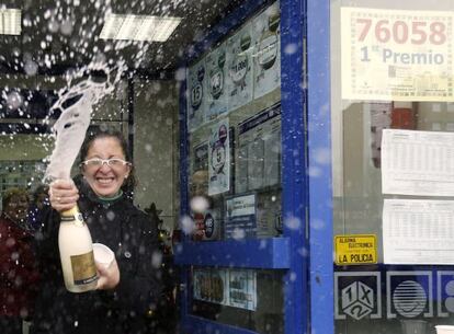 Una mujer descorcha una botella de champán en la administración número 12 de Alcalá de Henares, donde se han vendido 130 series del 76.058