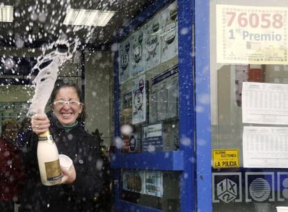 Una mujer descorcha una botella de champ&aacute;n en la administraci&oacute;n n&uacute;mero 12 de Alcal&aacute; de Henares, donde se han vendido 130 series del 76.058