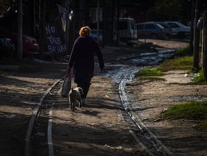 Una mujer camina por unas vías abandonadas junto a su perro en un suburbio de Buenos Aires.