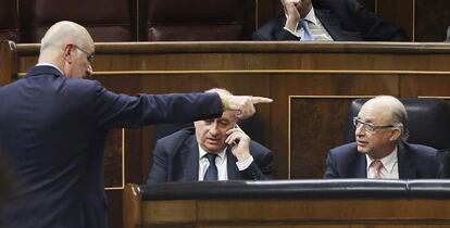 El portavoz de CiU en el Congreso, Josep Antoni Durán Lleida, a la izquierda, conversa con el ministro de Hacienda, Cristóbal Montoro, tras su intervención en el debate. Entre ellos, hablando por teléfono, el ministro de Interior, Jorge Fernández Díaz.