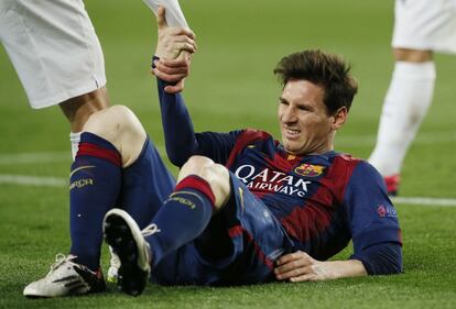 Un jugador del PSG ajuda Leo Messi a aixecar-se.