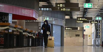 Un viajero transita por el aeropuerto de Madrid-Barajas con tiendas cerradas durante el estado de alarma.