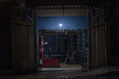 Un trabajador en el interior de un taller mecánico al caer la noche en Beirut.