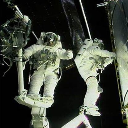 Dos astronautas trabajan en la puerta del telescopio <i>Hubble,</i> durante una misión de servicio del mismo.