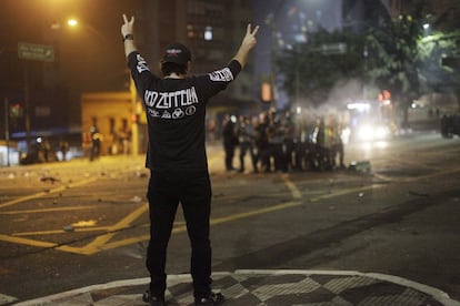 Un manifestante hace el gesto de la paz frente a agentes de policía.