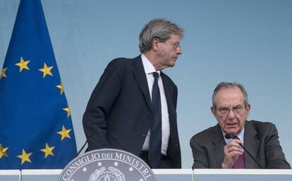 El primer ministro italiano, Paolo Gentiloni (de pie), y el ministro de Finanzas,  Pier Carlo Padoan, anuncian el rescate de dos entidades financieas en Roma, el 25 de junio. (Claudio Peri/ANSA via AP)