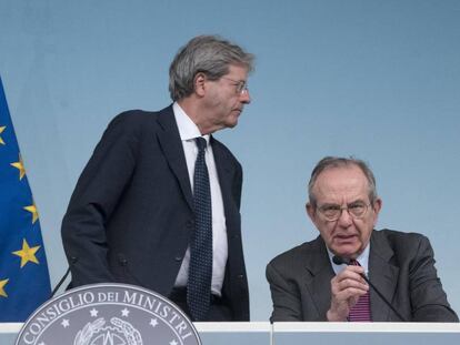 El primer ministro italiano, Paolo Gentiloni (de pie), y el ministro de Finanzas,  Pier Carlo Padoan, anuncian el rescate de dos entidades financieas en Roma, el 25 de junio. (Claudio Peri/ANSA via AP)