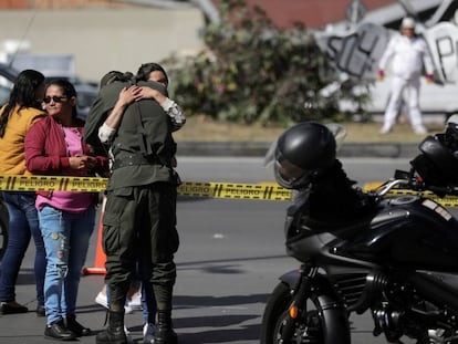 Una mujer abraza a un policía cerca del lugar del estallido de un coche bomba en la Escuela General Santander, en Bogotá. 