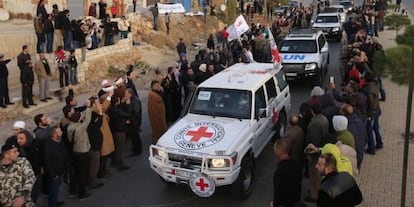 Un grupo de sirios tras cruzar el paso fronterizo libanés de Masnaa este lunes en un convoy de la Cruz Roja y la ONU.
