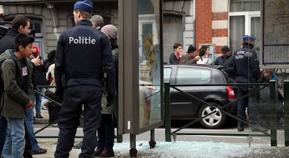 Un polic&iacute;a vigila al lado de un cristal roto por una explosi&oacute;n controlada, durante una redada en el barrio bruselense de Schaerbeek.