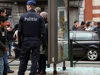 Un polic&iacute;a vigila al lado de un cristal roto por una explosi&oacute;n controlada, durante una redada en el barrio bruselense de Schaerbeek.