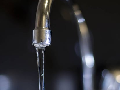 El agua mana de un grifo abierto en el fregadero de una vivienda.