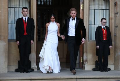 El principe Enrique y su ya esposa Meghan Markle saliendo del castillo de Windsor para la recepción de su boda.
