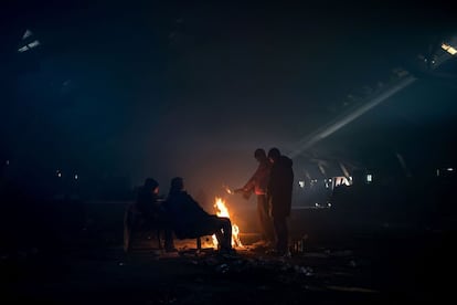 Un grupo de migrantes se calientan alrededor hoguera en una nave abandonada, a las afueras de Belgrado (Serbia).