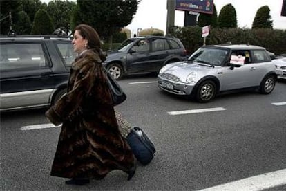 Una mujer se dirige a pie hasta la terminal de su vuelo con el equipaje a cuestas, en el aeropuerto de El Prat.