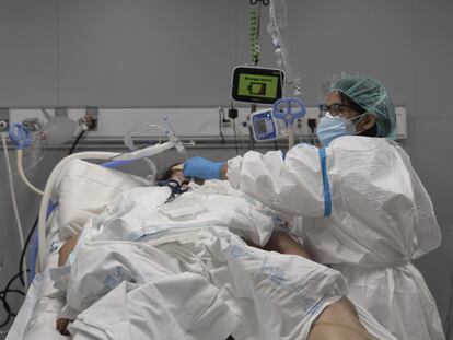Un sanitario atiende a un paciente ingresado en la UCI del Hospital Enfermera Isabel Zendal, en Madrid.