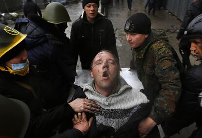 Un hombre herido lucha por respirar mientras es trasladado en camilla  por otros manifestantes antigubernamentales tras unos enfrentamientos con la policía antidisturbios en la Plaza de la Independencia en Kiev.