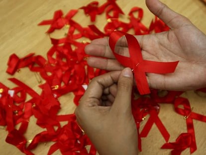 Una joven prepara lazos rojos en una campaña para la prevención del sida.
