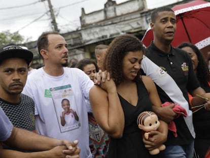 Vanessa Francisco Sales leva uma boneca que foi de sua filha, Ágatha Félix. Está de mãos dadas com Adegilson Félix, seu marido e pai da menina, durante o velório.
 