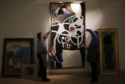 Christie&acute;s auction house workers adjust one of the paintings by Joan Mir&oacute; which Portugal&#039;s government hopes to sell.