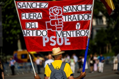 Un manifestante sujeta una pancarta contra el secretario general del PSOE y presidente del Gobierno, Pedro Sánchez, este domingo, en la plaza de España de Madrid.