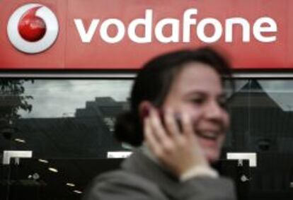 Una cliente habla por el m&oacute;vil frente a una tienda Vodafone