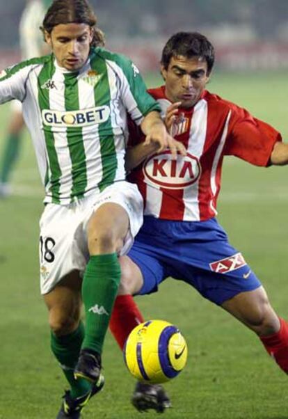 El jugador del Betis, Rivera (izquierda), controla la pelota frente al jugador del Atlético, Ibagaza.