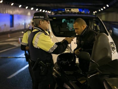 Un agente de la Guardia Urbana de Barcelona hace la prueba de alcoholemia a un motorista.