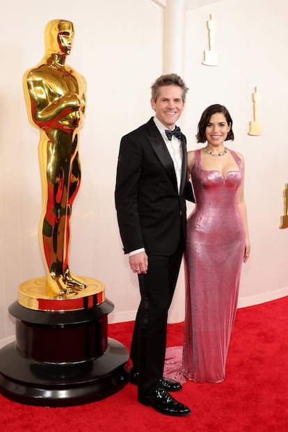 Ryan Piers Williams y America Ferrera, pareja en 'Barbie' y en la vida real. Ella estaba nominada como mejor actriz de reparto y su vestido, rosa y brillante, es un guiño al color estrella de la película. Se trata de un modelo metálico a medida firmado por Atelier Versace, que ha combinado con joyas de Pomellato.