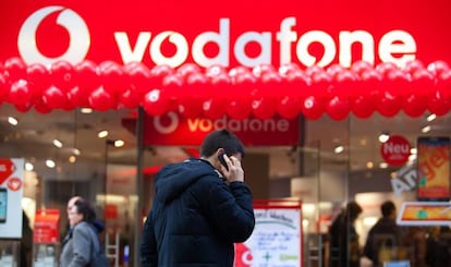 Un hombre habla por telef&oacute;no, ante una tienda de Vodafone.