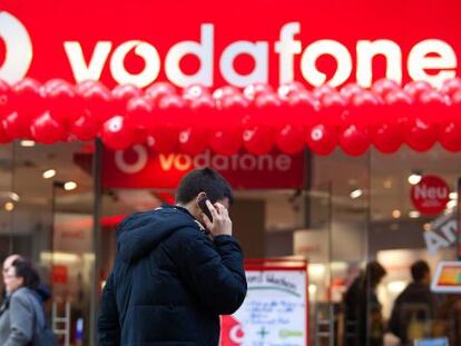 Un hombre habla por telefóno, ante una tienda de Vodafone.