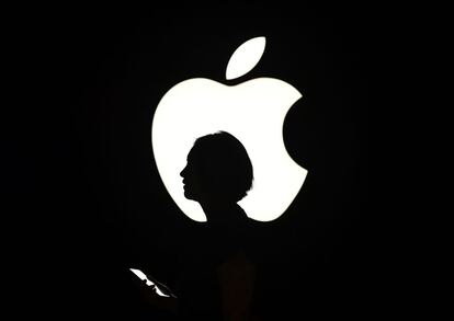 Una mujer pasa delante de un cartel con el logo de Apple en San Francisco, en septiembre de 2015. 