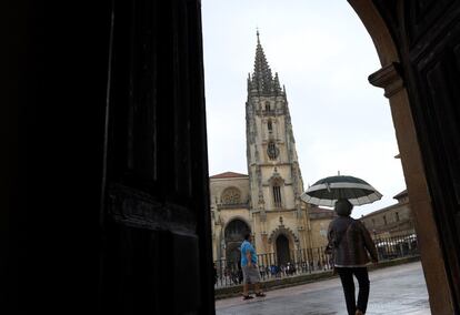 Varias personas caminan con paraguas y chaquetas por el centro de Oviedo, este jueves.