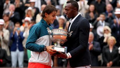 Usain Bolt entrega el trofeo de campeón de Roland Garros a Nadal.