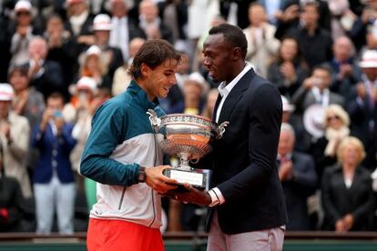 Usain Bolt entrega el trofeo de campeón de Roland Garros a Nadal.