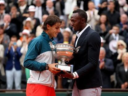 Usain Bolt entrega el trofeo de campeón de Roland Garros a Nadal.