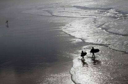 Surfistas salen del agua durante un día inusualmente cálido en la playa de Biarritz (Francia).