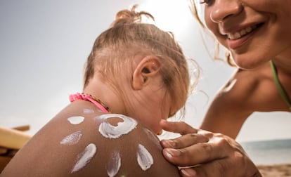 Una madre echa crema solar a su hija.