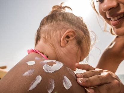 Una madre echa crema solar a su hija.