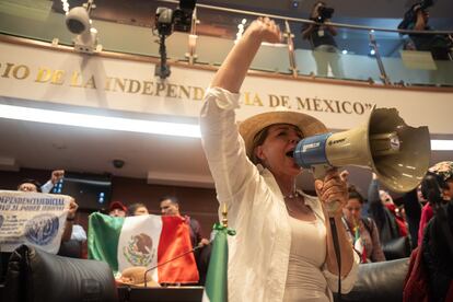 Una mujer grita arengas con un megáfono tras irrumpir en la sede regular del Senado.