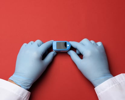 electronic pulse oximeter in the hands of a doctor, wearing blue latex gloves