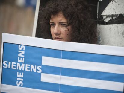 Una activista griega protesta en Berl&iacute;n con una bandera que incluye el nombre de una empresa alemana.
