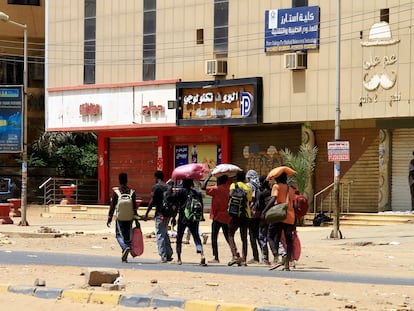 Varias personas con sus pertenencias caminaban el domingo por una calle de Jartum, mientras continuaban los enfrentamientos entre las fuerzas de dos generales rivales.