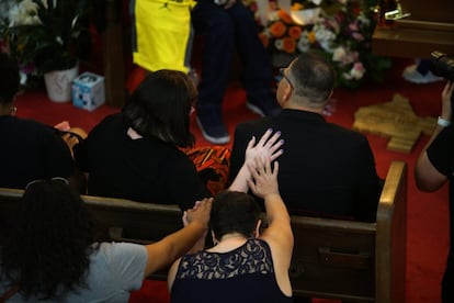 Dos asistentes ponen sus manos en la espalda de Dean Reckard, el hijo de Margie Reckard de una relación anterior a su matrimonio con Antonio Basco, durante el funeral. A la presencia de cientos de personas se unen más de mil coronas y arreglos florales recibidos de la zona y desde el extranjero.