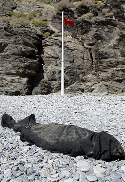 El inmigrante fallecido yace tapado con una tela negra a la espera del levantamineto del cadaver.