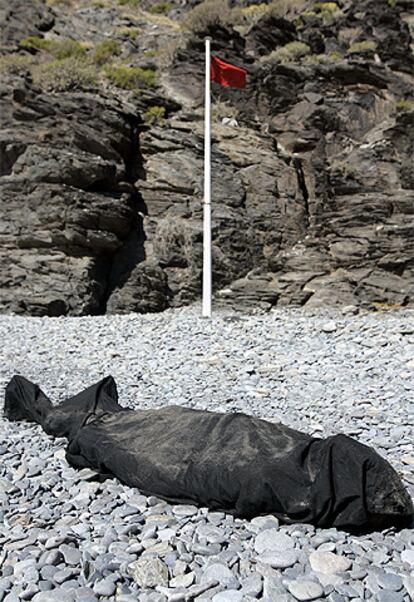 El inmigrante fallecido yace tapado con una tela negra a la espera del levantamineto del cadaver.