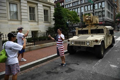 Un hombre vestido con la bandera de Estados Unidos posa para una fotografía junto a un Humvee del Ejército estadounidense aparcado en una calle de Washington.